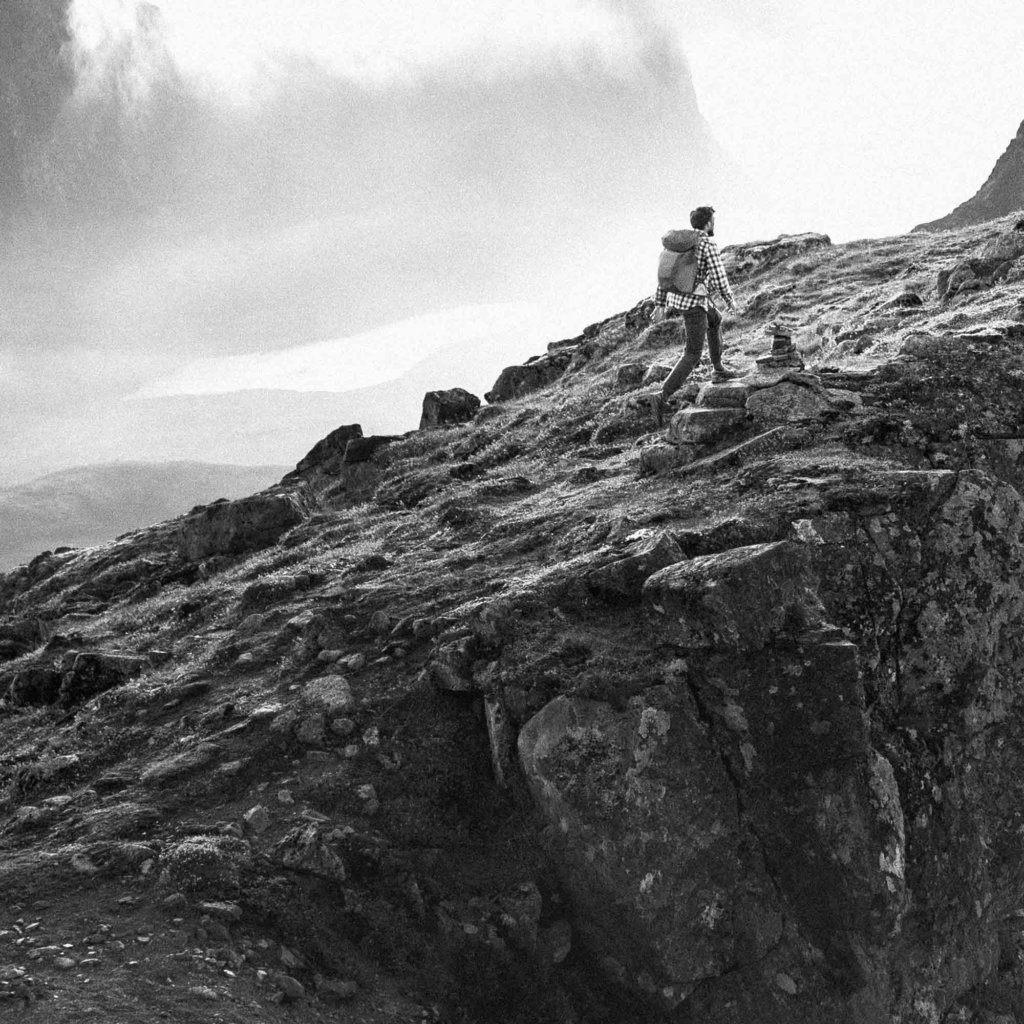 Black and white grainy image of a man standing on a mountain