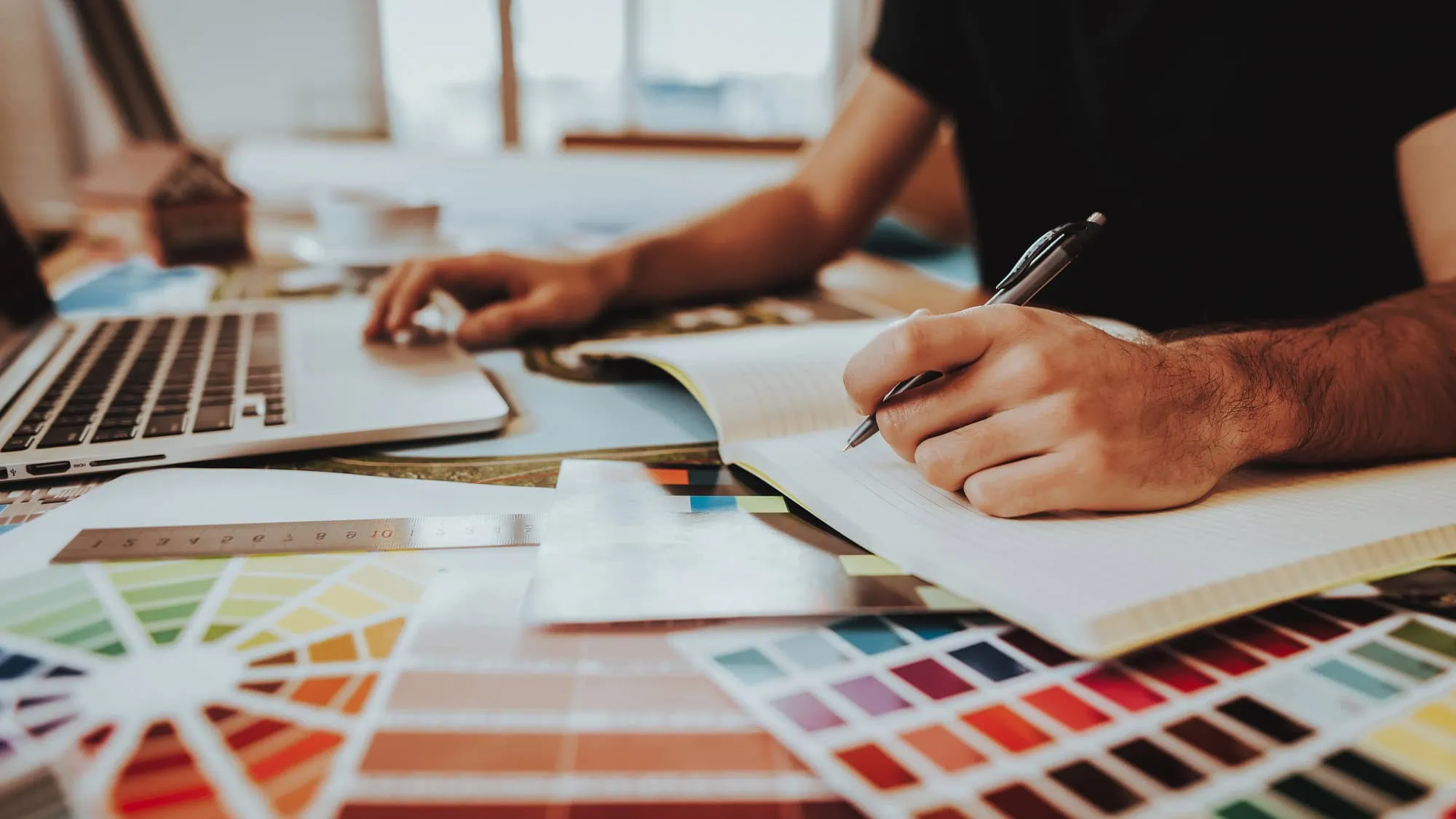 tinybox creative - Bristol creative agency graphic designer working at a desk with colour charts and a MacBook Pro